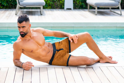 Modèle allongé au bord d'une piscine, en boxer "APPACH" de "By Radouane", reflétant un luxe décontracté avec des matériaux haut de gamme et un design français.